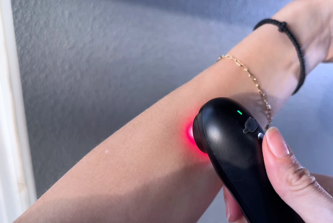 STOGA IRH-1 white ceramic contact surface held flat against intact skin with visible red light